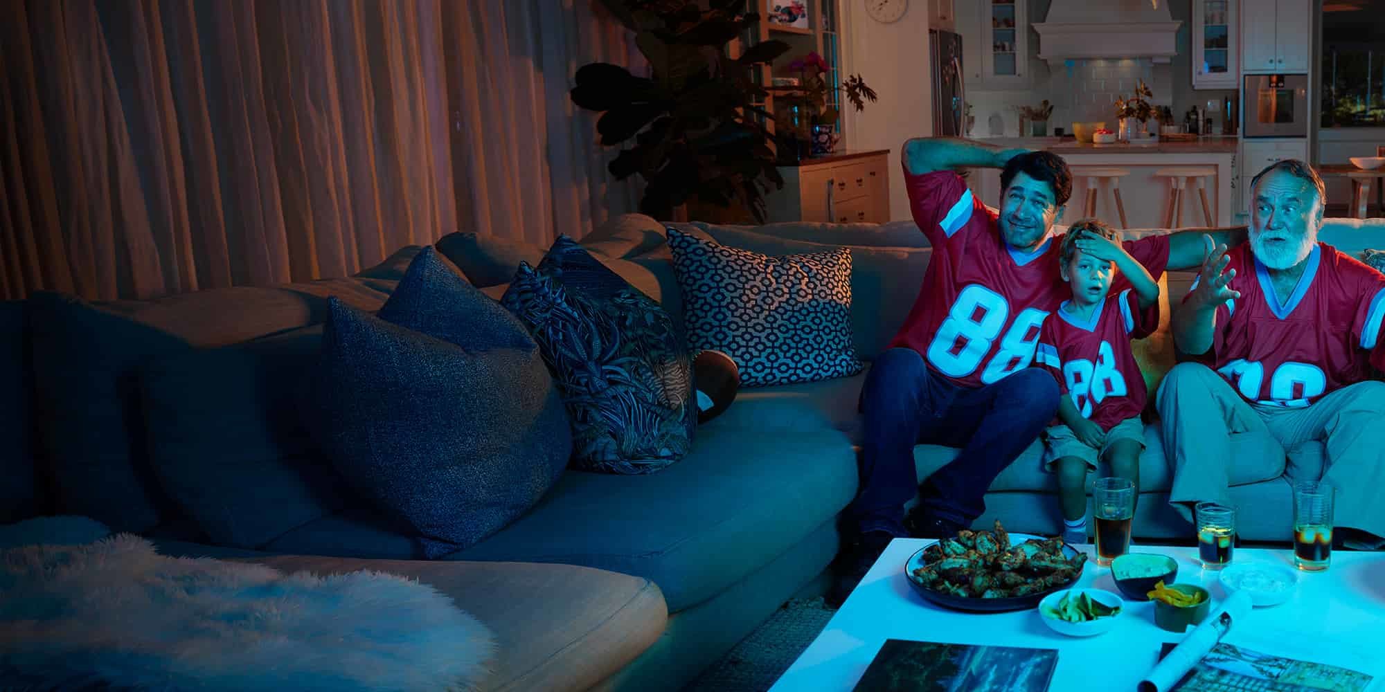 Grandpa, dad, and son watching a football game.
