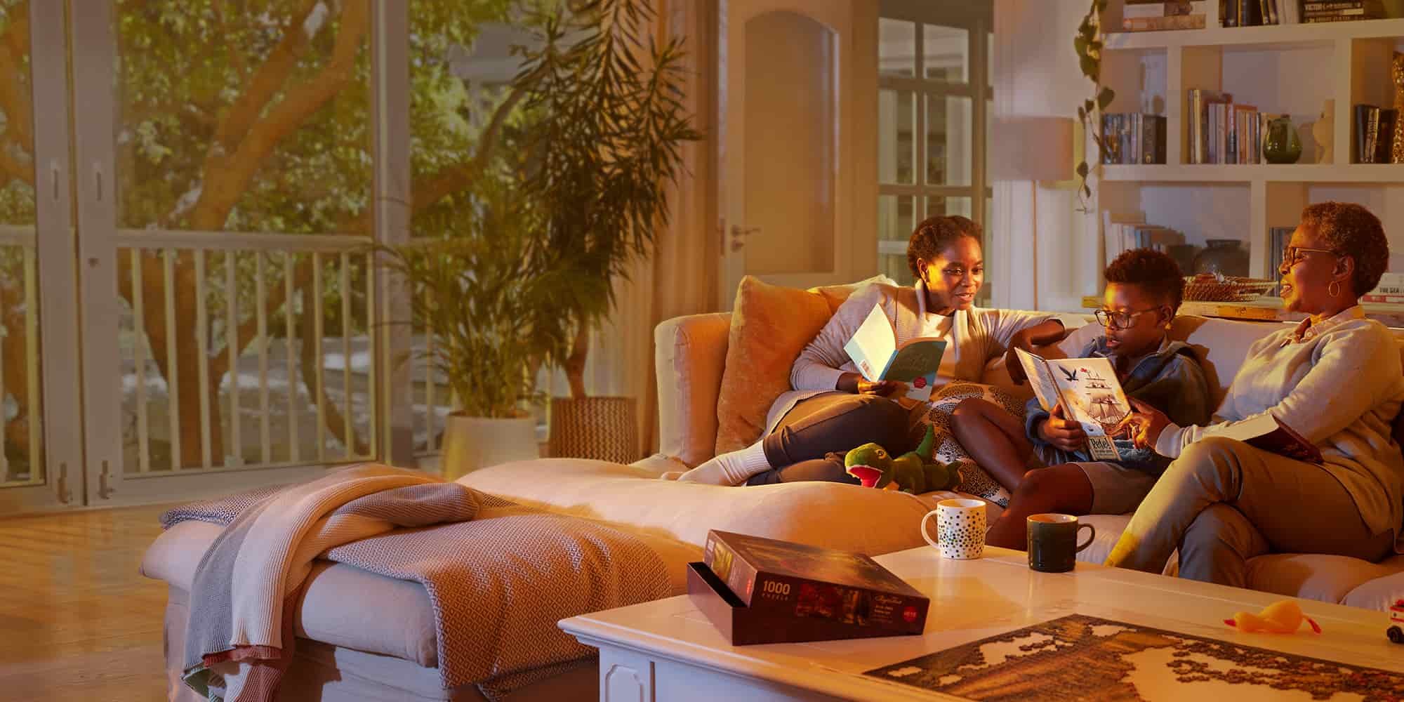 Grandma, mom, and grandson reading books on a couch.