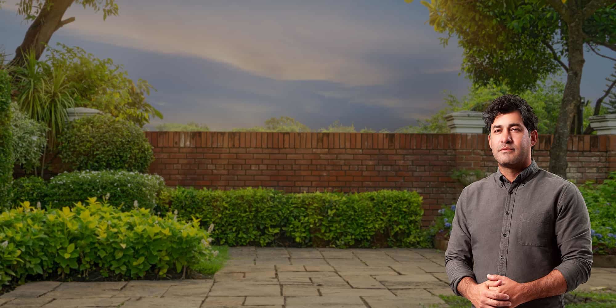 Man standing outside with hands folded.