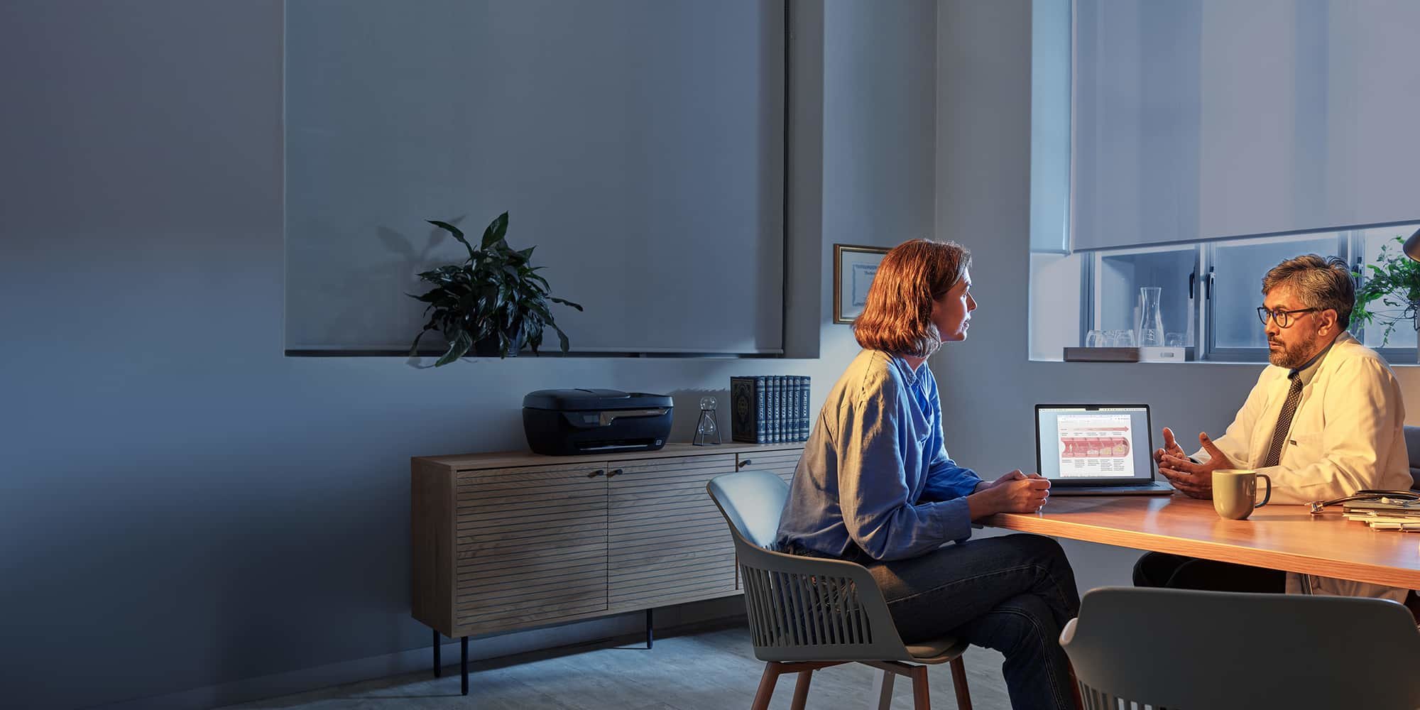Woman and doctor sitting at a desk talking in the doctor’s office.